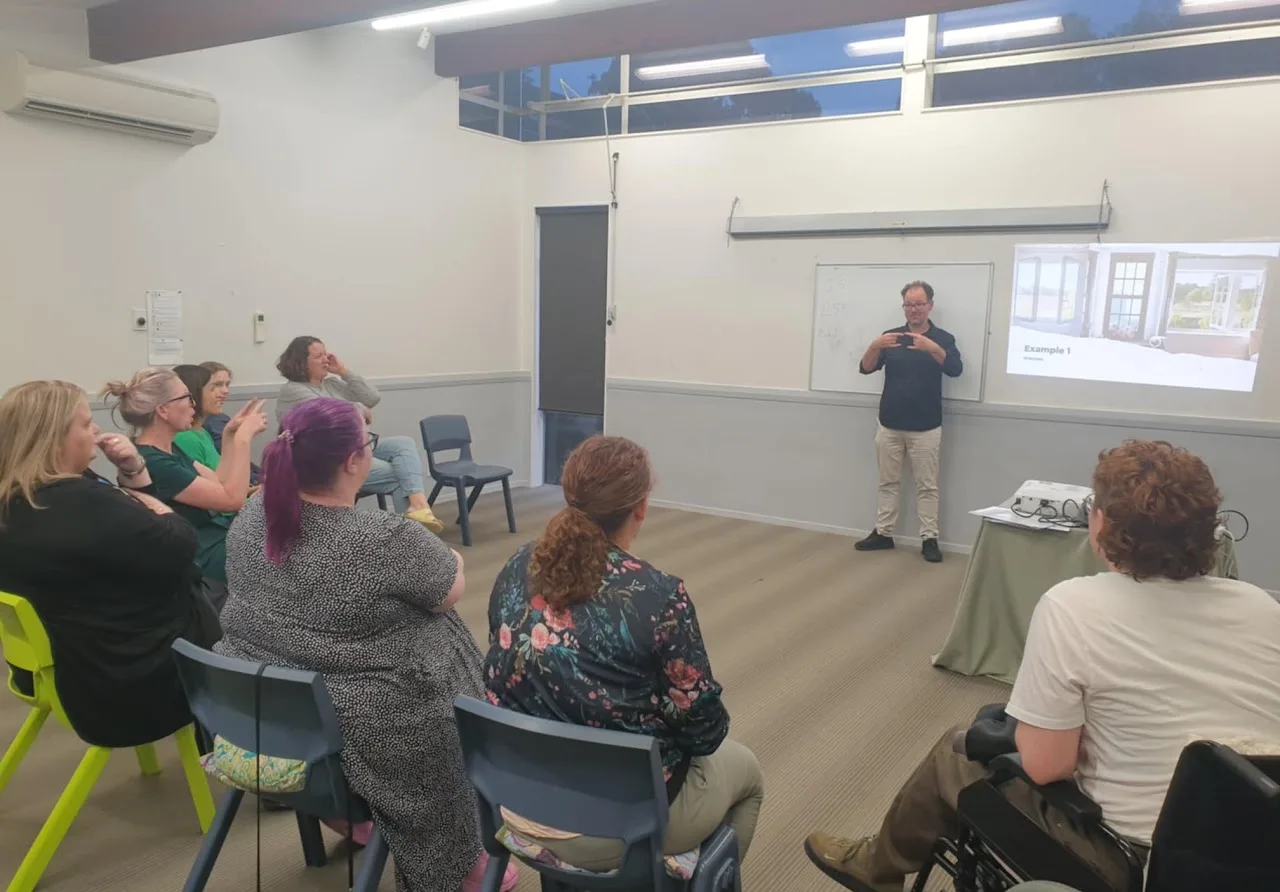 Pascal Pasou presenting to a seated group about the 100th Deaflympics, November 2024